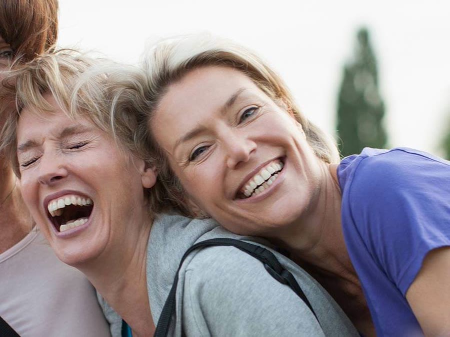 Two women laughing with bright, confident smiles
